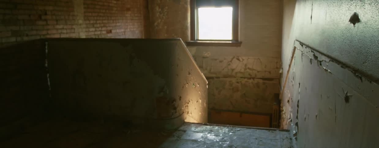 A stairway with a handrail with a window and a wall in the background