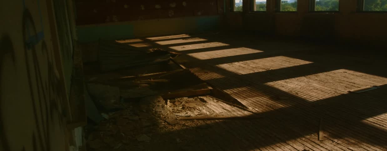 Sunlight shines in through the windows onto the debris in a derelict building on a sunny