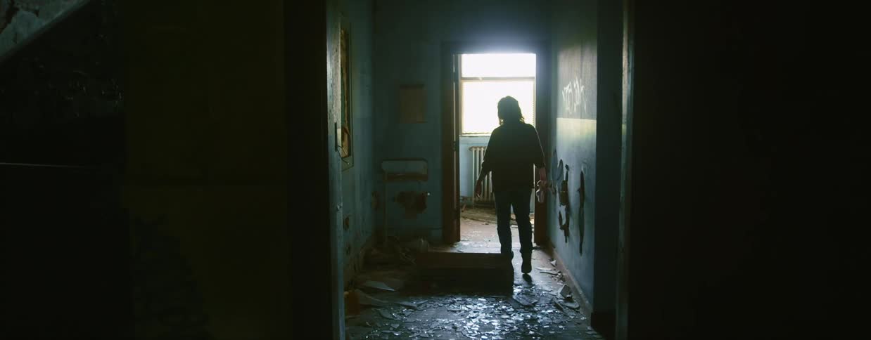 A woman walks through a decrepit building during the day