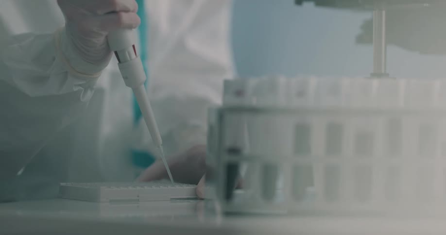 A lab technician is filling a tray with a needle