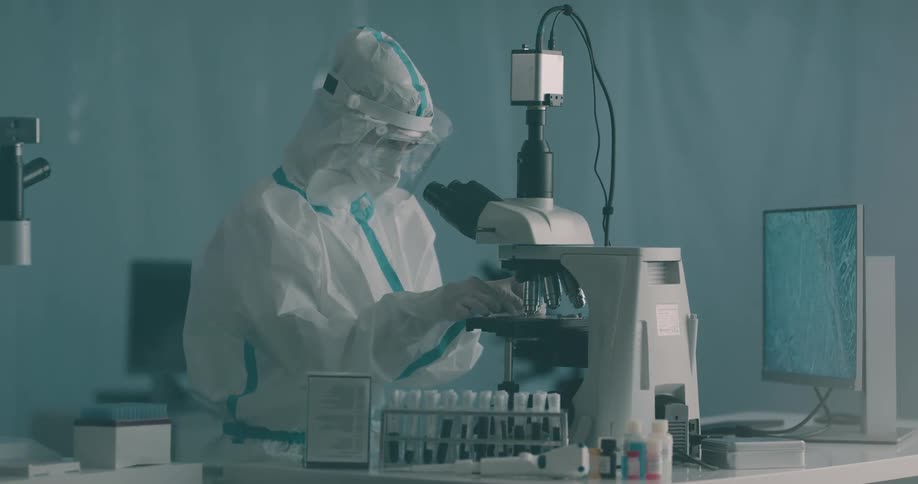 Technician places glass slide under a microscope in a laboratory