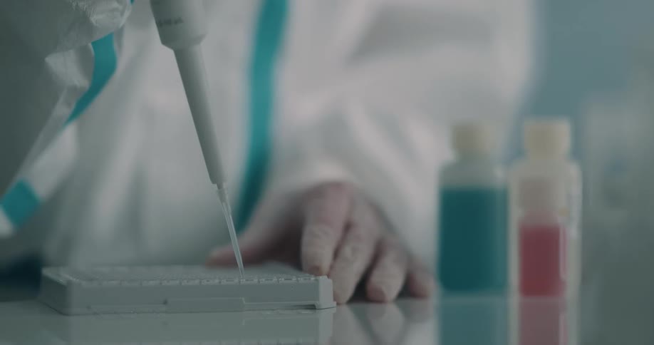 A lab worker uses a pipette to add liquid to a sample tray