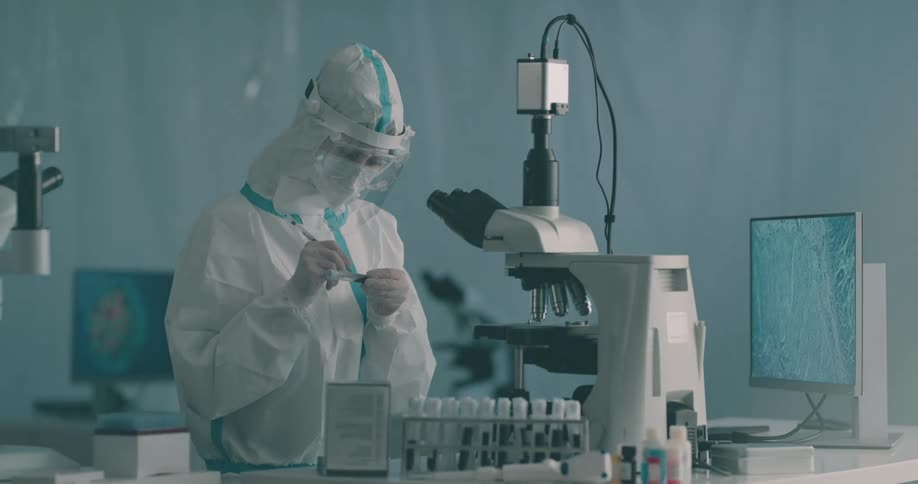 A scientist picks up a vile writes on it and places it back into a holder