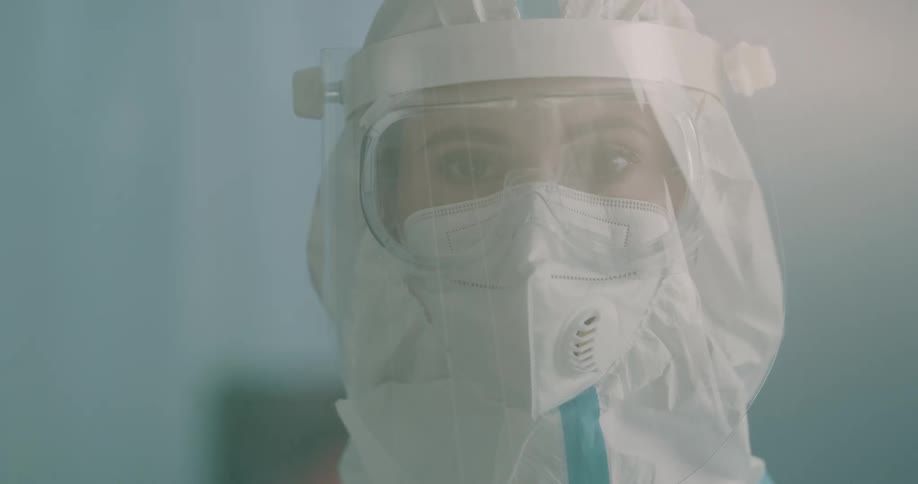 A lab worker poses in full protective wear with goggles and a mask