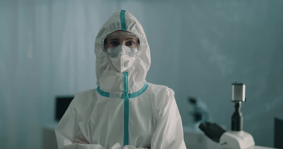 Young lab technician wearing protective gear in a laboratory looks at the camera