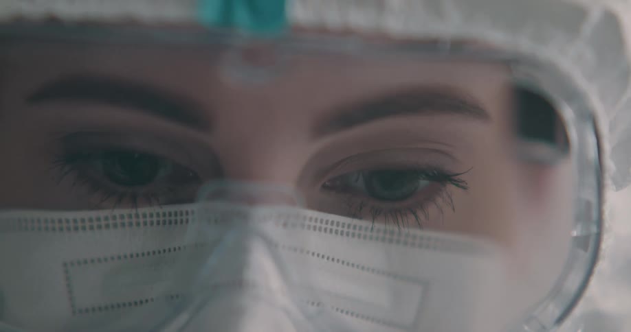 A woman wearing a mask and goggles with only eyes visible