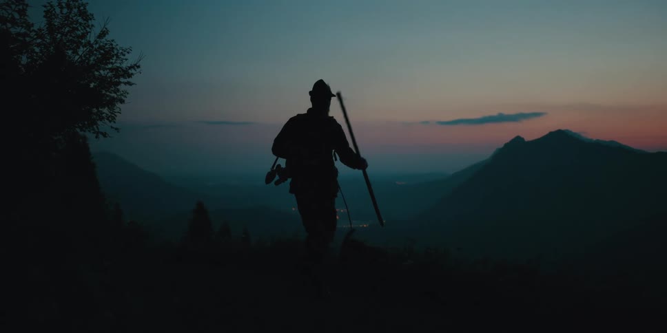 A man is hiking outdoors at dusk