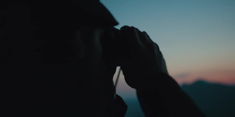 A man is looking at the horizon with binoculars