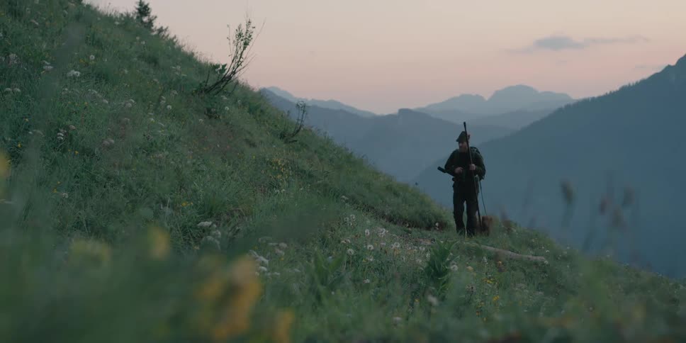 A man and his dog are hiking at dusk