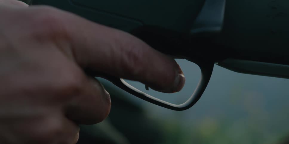 A person with their hand on a firearm pulling a trigger