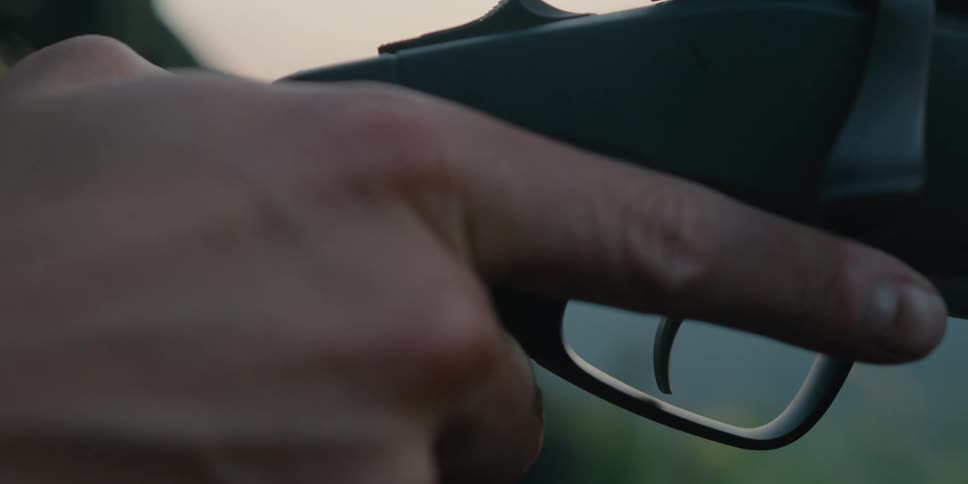 A young man puts his finger on a trigger on a gun and gets ready to shoot