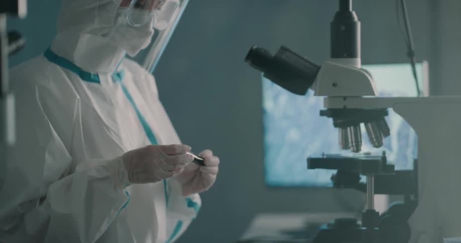 A scientist picks up a vile of blood and examines it