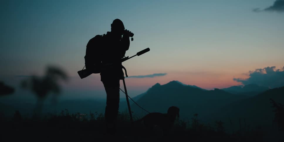A man is hiking with his dog at dusk