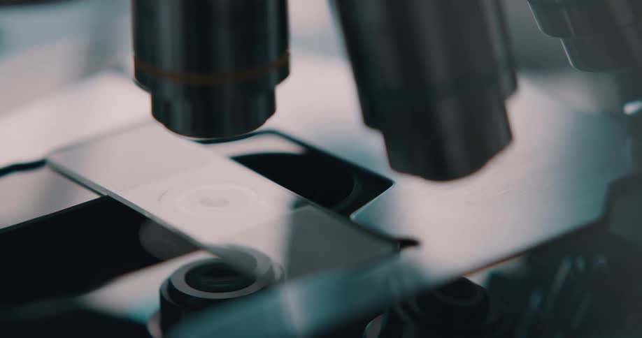 Lab technician places a slide under the lens of a microscope