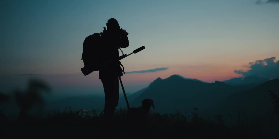 A man is hiking with his dog at dusk