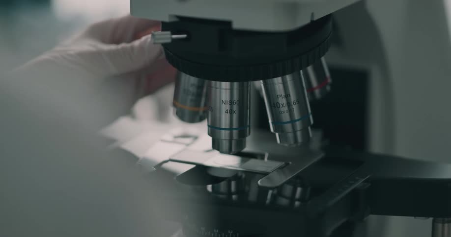 A woman adjusts a microscope