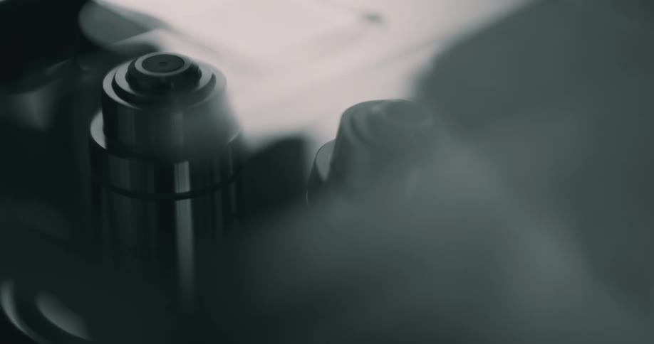 A microscope with its lens being rotated with reflection and light