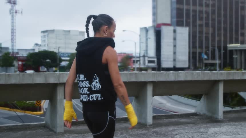 A physically fit woman walks across an open parking garage in a large city