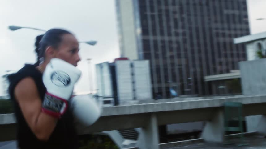 Female boxer and trainer do boxing training on top of a building in the city