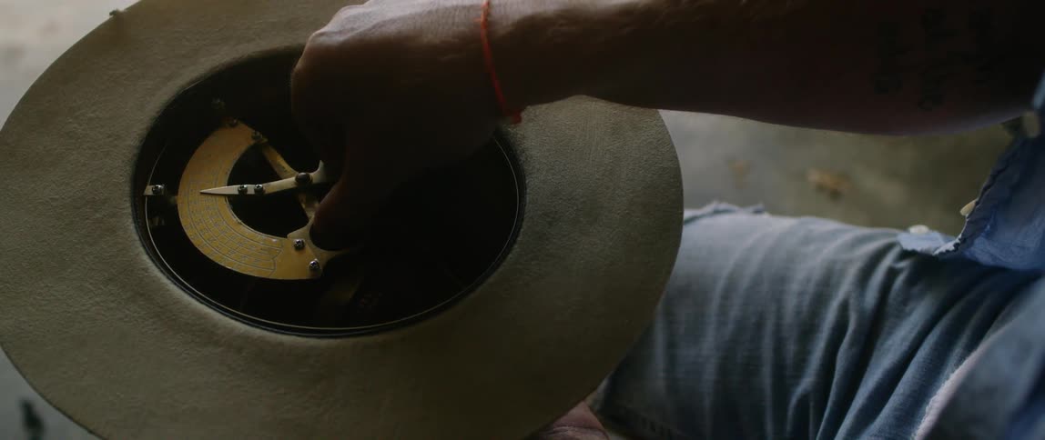 A man sitting and holding a hat measures it