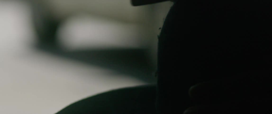 A persons hand using a tool on a hat with a window in the background