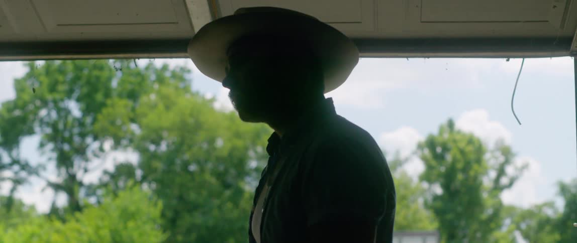 Silhouette of a man wearing a cowboy hat inside a garage at home