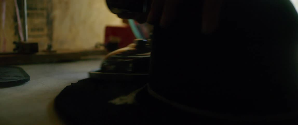 A person in a garage ironing a hat with an iron
