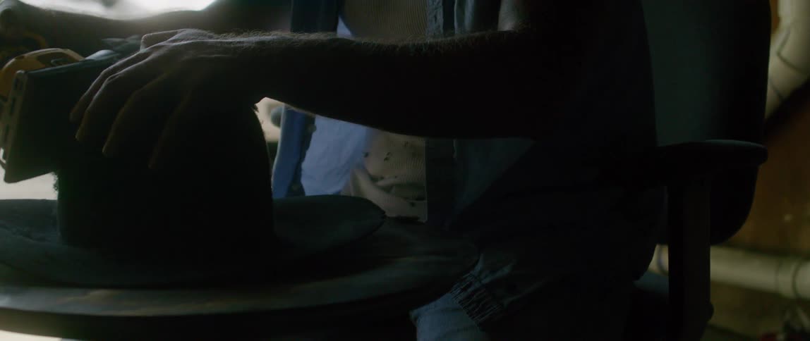 A man is using a sander on a hat