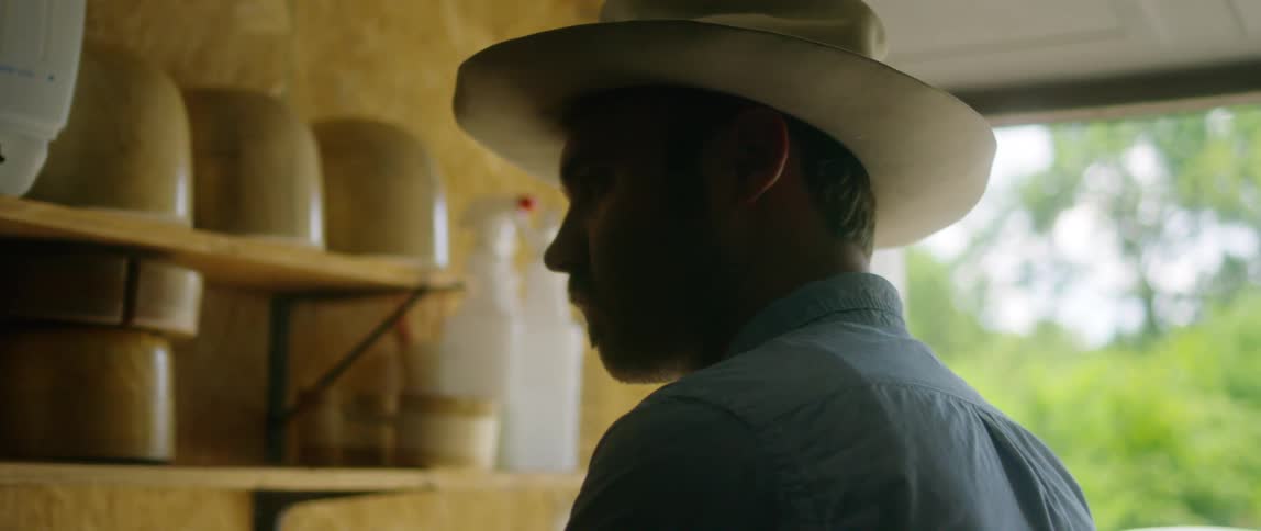 A man stands in his garage by shelves of hat holders
