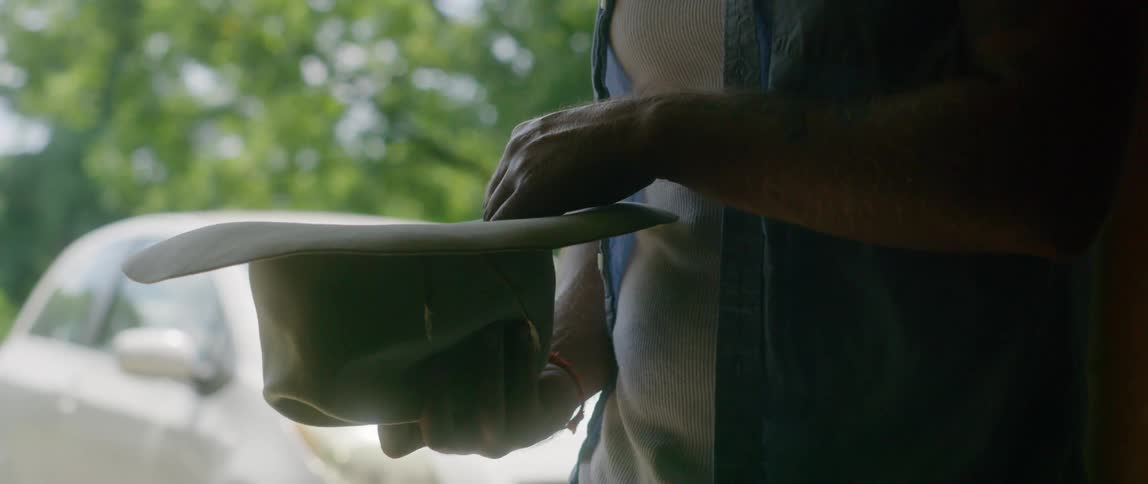 A man in his garage tries a cowboy hat on