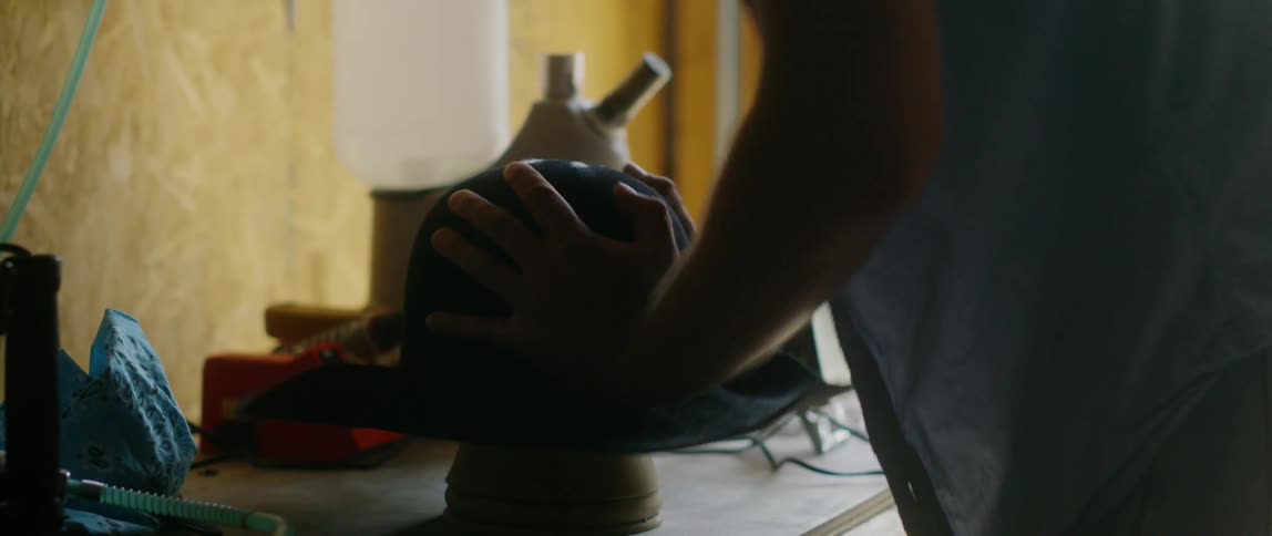 A man is forming a hat on a stand