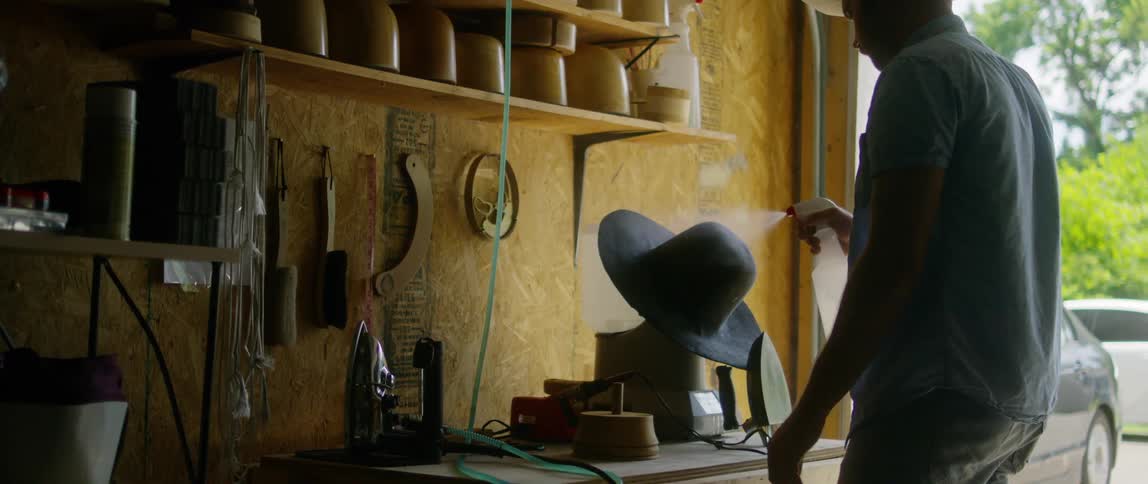 A man is cleaning his hat in the garage