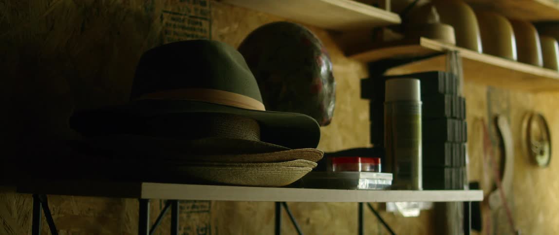 A shelf with hats and a spray can with a wall in the background