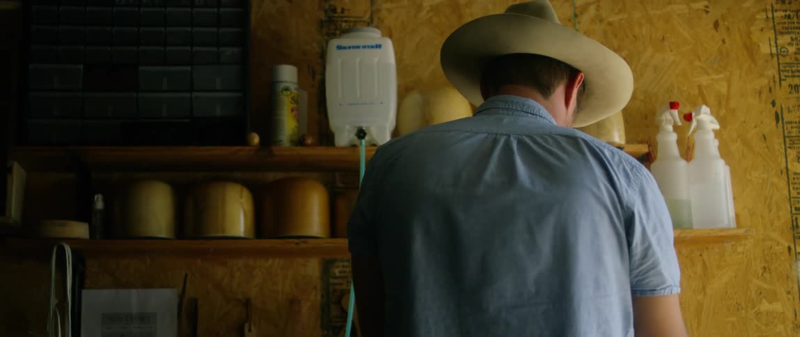 A man in his garage walks over to a shelf