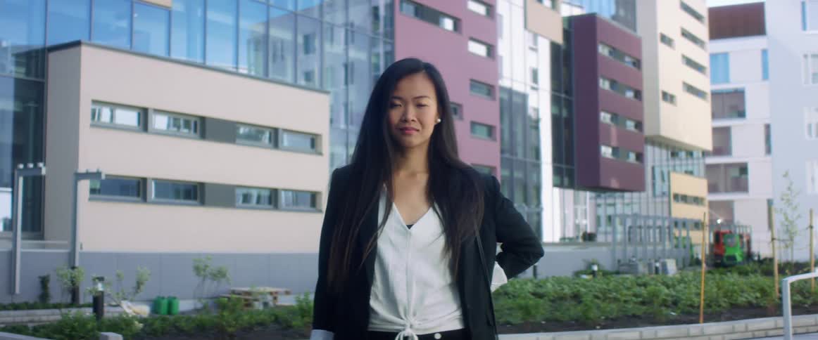 An asian woman is standing in a downtown city