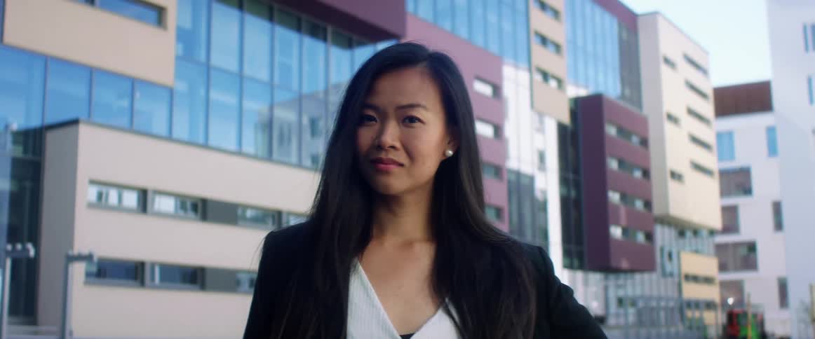 A young asian woman standing outside of office buildings