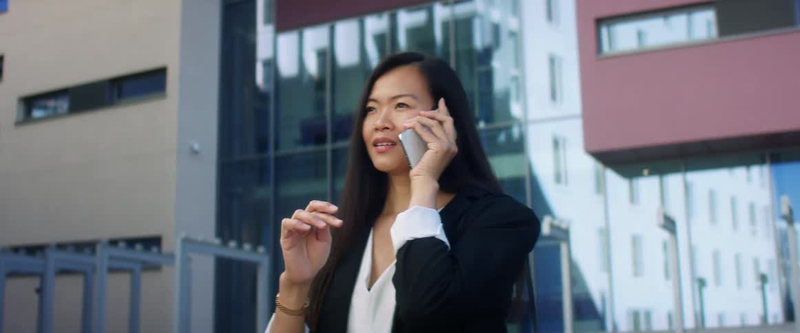 Business woman talks on her smartphone outside a building in the city