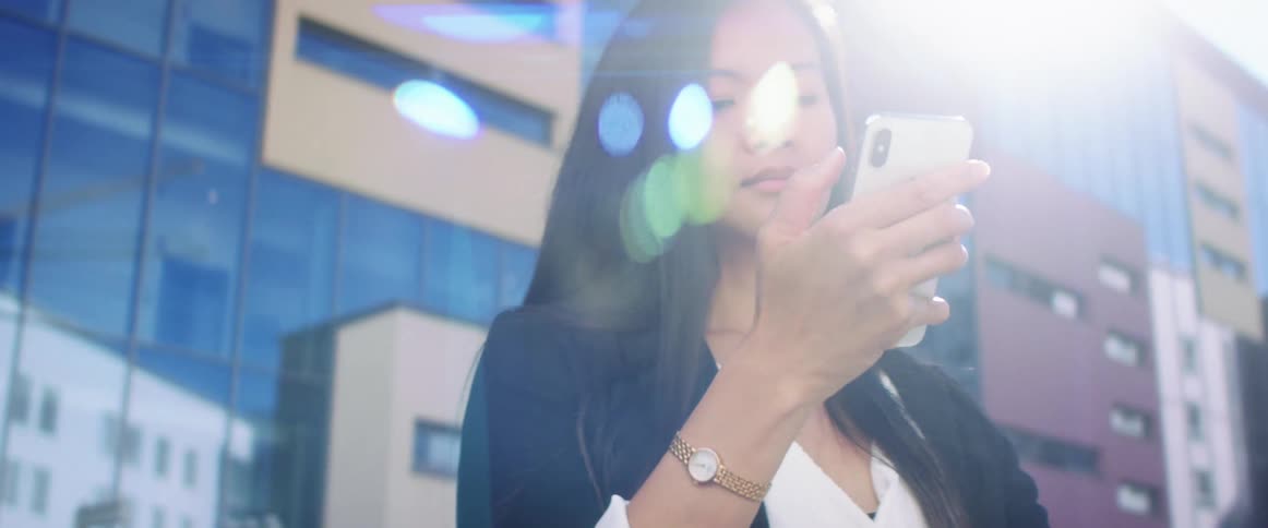 A woman is texting on a cell phone in a downtown city