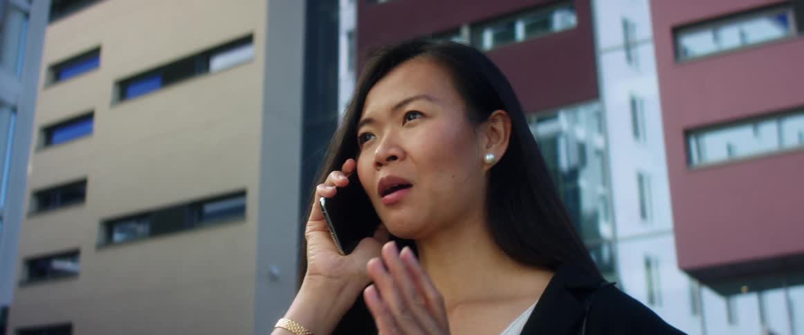 A woman talking on a smart phone with buildings and windows in the background