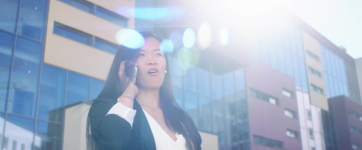 Young woman answers a call on her smart phone in the city