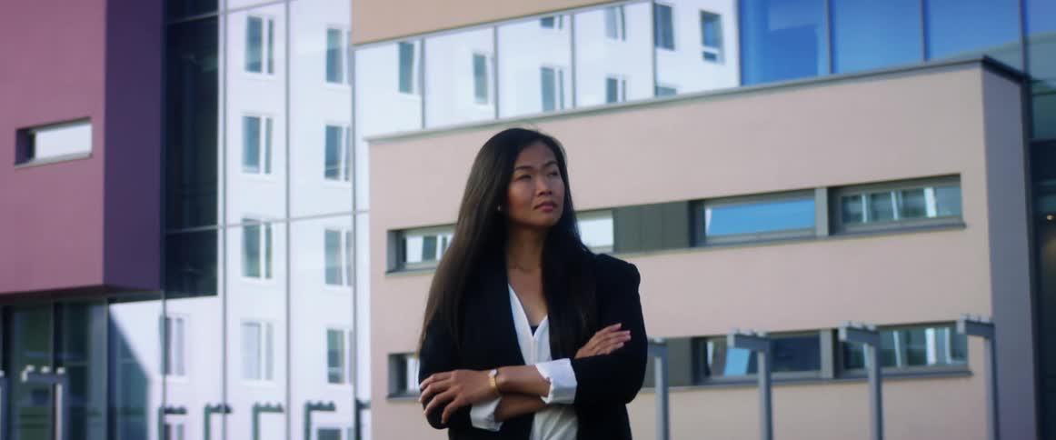 Woman stands outside a building with her arms closed