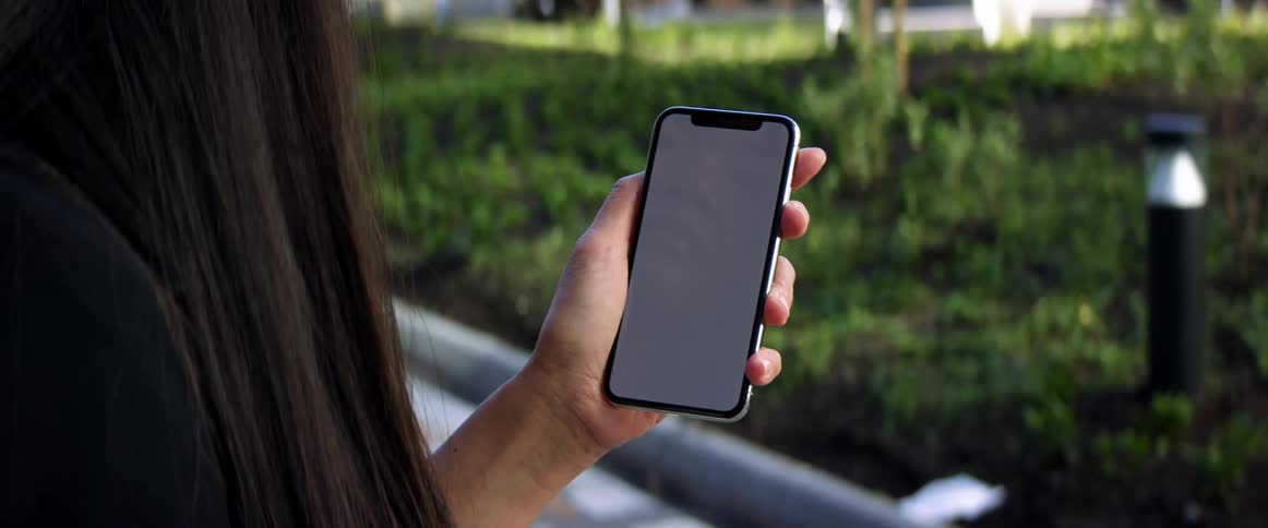 A woman is looking at a cell phone outdoors