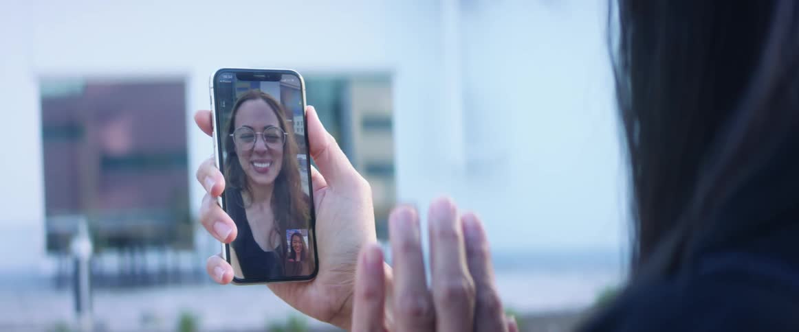 Woman waves to friend on video chat on cell phone