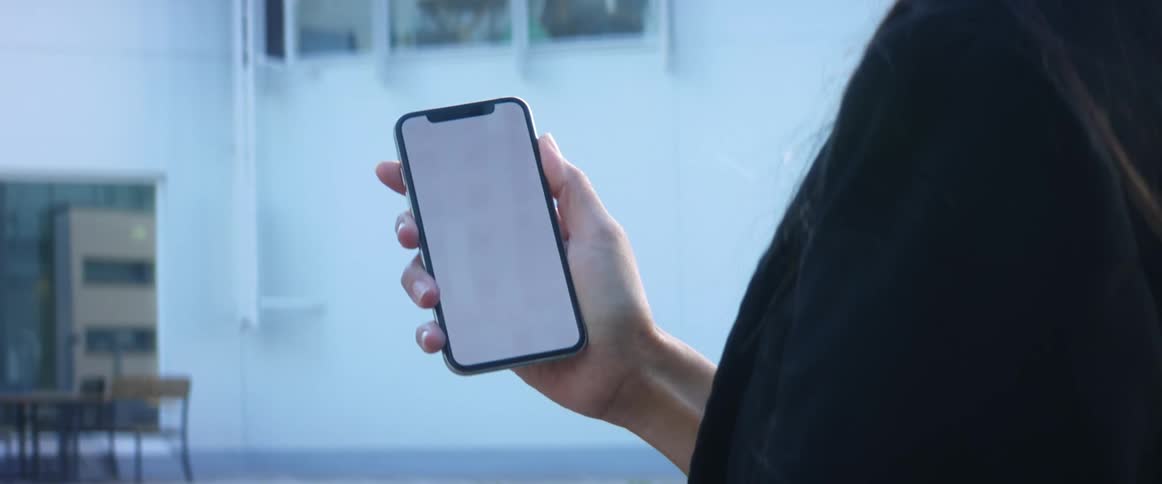 A woman holds her cell phone in her hand and looks at a white screen