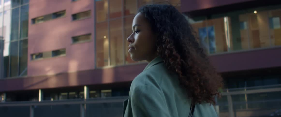 A woman with a notebook and pen walking in a city and writing