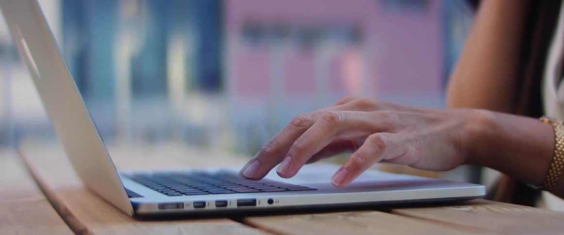 Womans hand types on a macbook pro keyboard