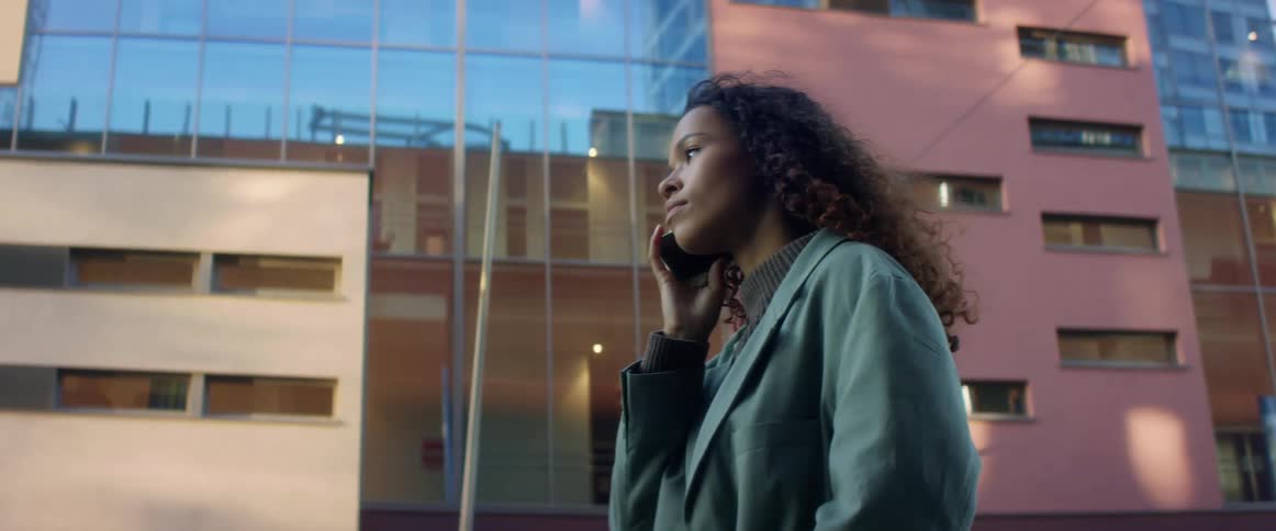 Woman answers a phone call on her smart phone outside a door in the city