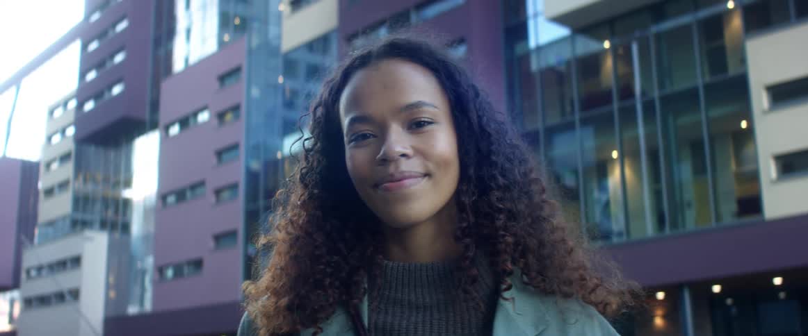 A woman is smiling by the buildings