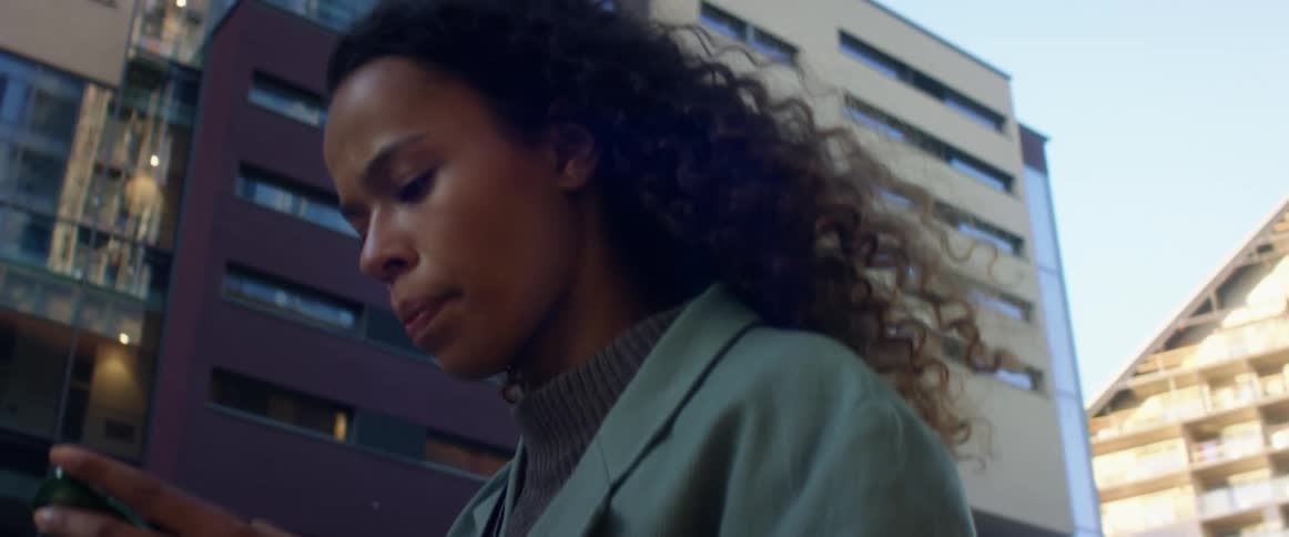 A woman looks at her cell phone as she walks outside of office buildings