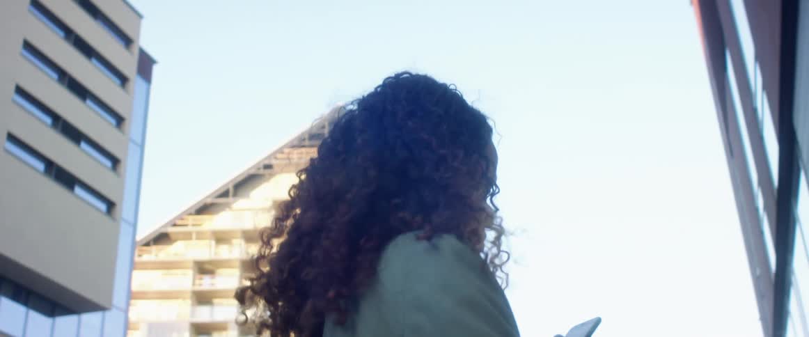 Young woman holding a phone turns around on the street of a city
